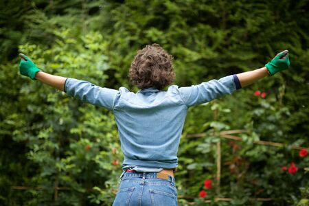 Portrait from behind female gardener with arms outstretched