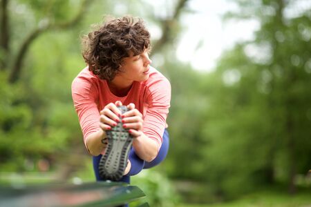 Portrait sport woman stretching leg muscles outdoors