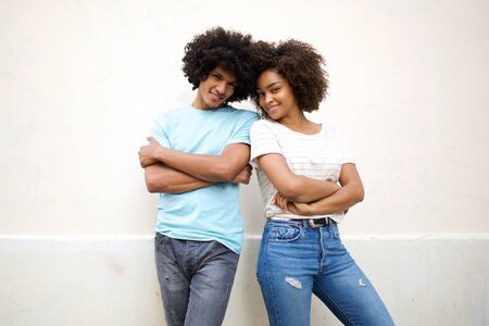 Portrait of cool young african american couple standing against white background with arms crossedの写真素材