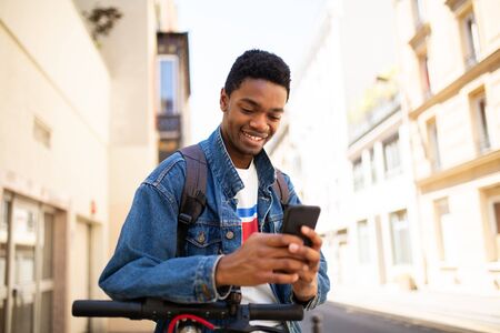 Portrait of cool african american young man looking at mobile phone in city