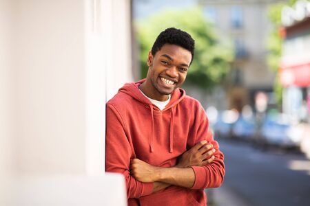 Portrait smiling african american man leaning against wall with arms crossed