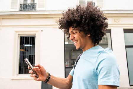 Side portrait of happy young arab man walking and looking at cellphone