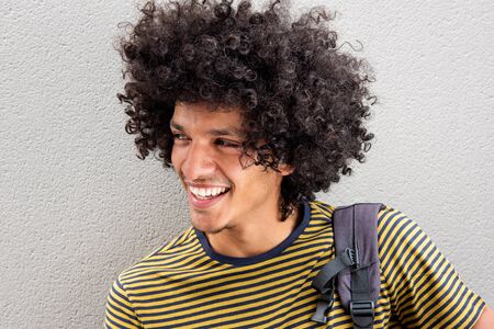 Close up portrait of handsome young North African man with afro hair smiling and looking away