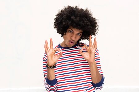 Front portrait of young african american man with afro hair and ok hand sign against isolated white backgroundの写真素材