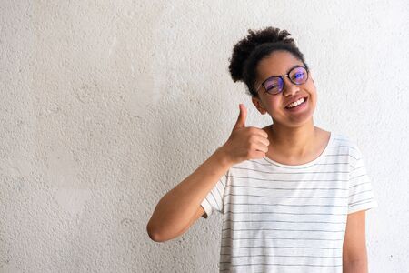 Portrait happy young black girl with thumbs up hand signの写真素材