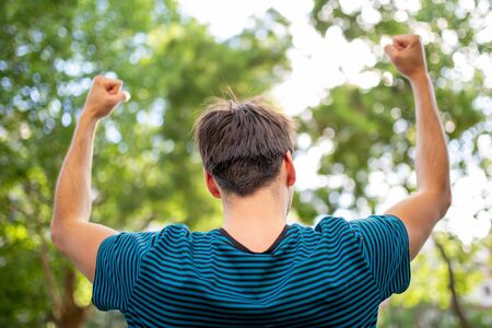 Portrait of back of cheerful young man with arms raisedの写真素材