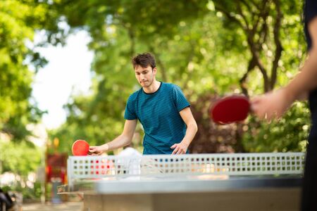 Portrait of young man playing table tennis in parkの写真素材