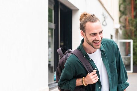 Portrait of young man with backpack laughing in cityの写真素材