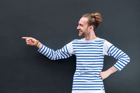 Portrait smiling man pointing finger to empty space on black backgroundの写真素材