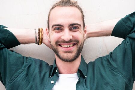 Close up portrait of smiling man with beard and hands behind head