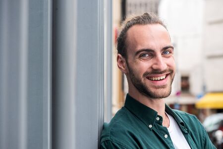 Close up portrait of smiling young man with beard in cityの写真素材