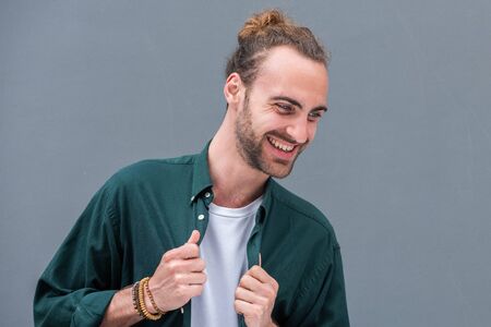 Close up horizontal portrait of young man with beard against gray background laughing and looking awayの写真素材