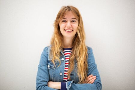 Front portrait of smiling young woman with arms crossed against white backgroundの写真素材