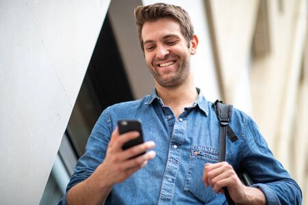 Close up portrait happy man looking at cellphone outsideの写真素材