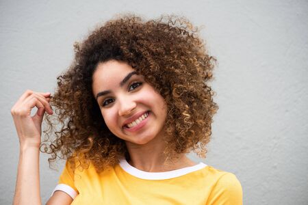 Close up portrait cute young woman with curly hair by gray background