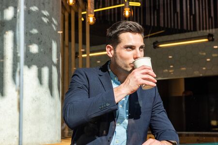 Portrait of young businessman sitting at cafe drinking coffee