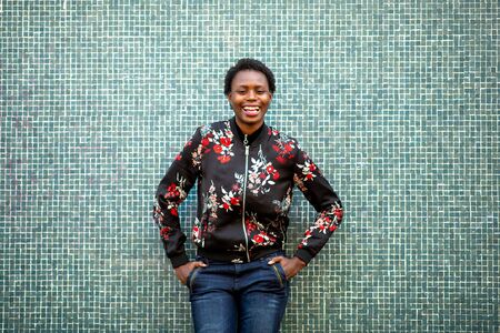 Portrait happy young african woman laughing by green wallの写真素材