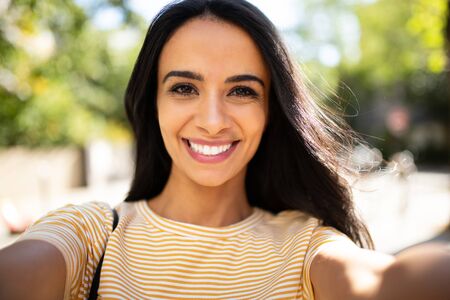 Close up selfie portrait smiling North African young woman outside