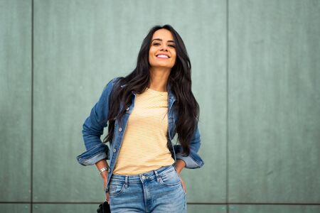 Close up portrait smiling young arab woman posing by green wall