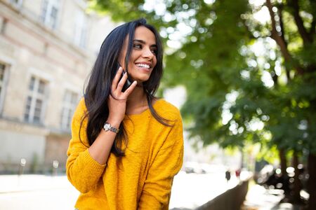 Close up portrait smiling young latin woman talking with cellphone in city