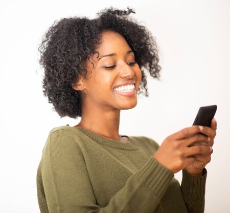 Close up portrait smiling young african american woman using mobile phone against isolated white...