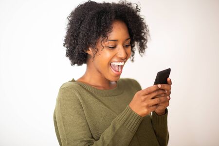 Close up portrait smiling young african american woman using cellphone against isolated white backgroundの写真素材