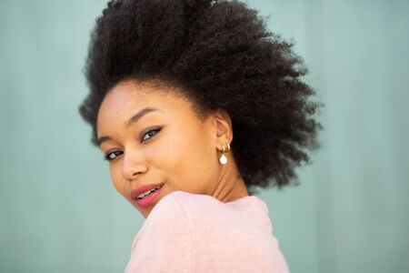 Close up portrait beautiful young black woman with afro hair by green background