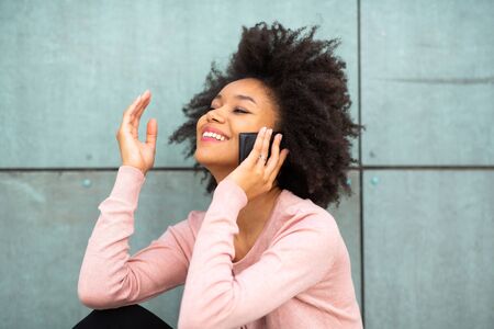 Portrait happy african american woman sitting talking with cellphoneの写真素材