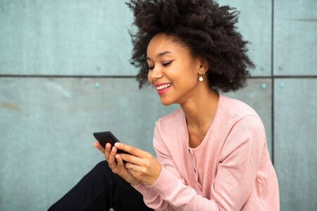 Close up portrait happy young african american woman looking at cellphone