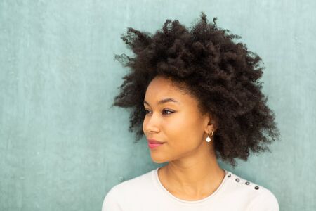 Close up portrait beautiful young african american woman with afro hair by green backgroundの写真素材