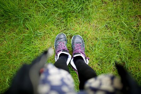 Top view female shoes and legs standing on green grassの写真素材