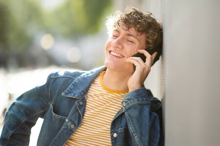 Close up portrait smiling young man talking with mobile phone in city