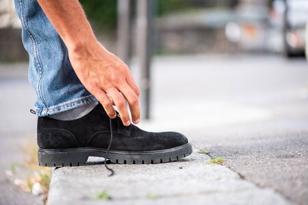 Close up side man hand tying shoelace on sidewalk の写真素材