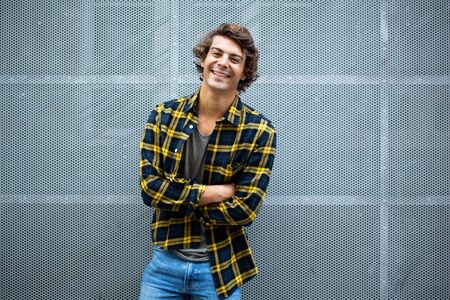 Portrait handsome young man smiling with arms crossed by gray wallの写真素材