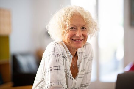 Close up portrait smiling older woman at homeの写真素材