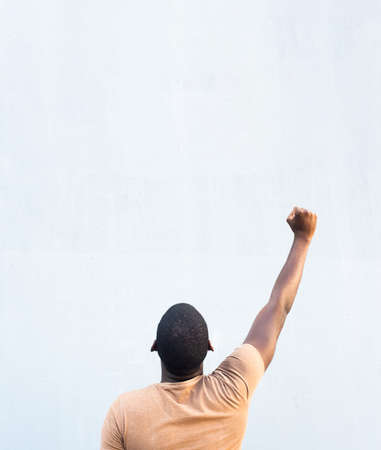 Portrait from behind young black man with arm raised and fist pump in the air