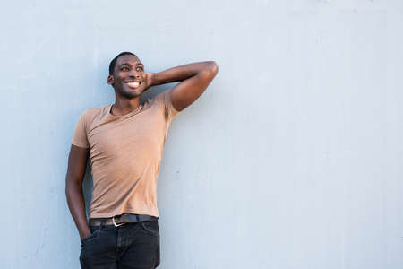 Portrait cool young African American guy relaxing with hand behind head by gray backgroundの写真素材