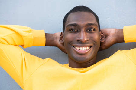 Close up portrait happy young African American man with hands behind headの写真素材