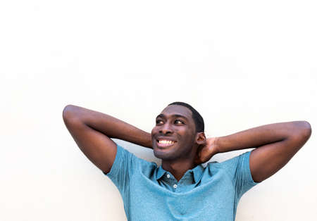 Close up portrait relaxed young black man smiling with hands behind head against white background