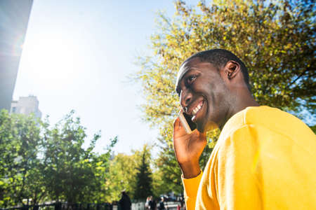 Close up side portrait young black man talking with mobile phone outsideの写真素材