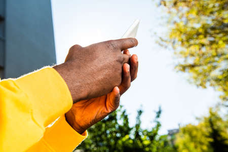 Close up African American male hands holding cellphone outside