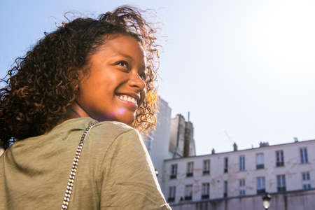 Close up portrait young woman with curly hair looking over shoulder and smilingの写真素材