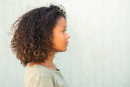 Profile portrait young African American woman with curly hair against green backgroundの写真素材
