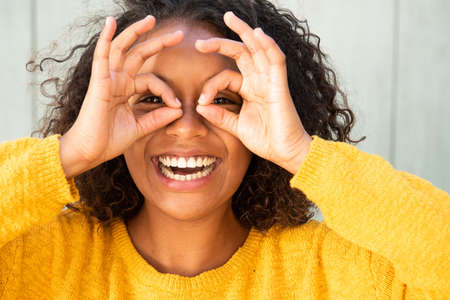 Close up portrait happy young woman making eye glasses with hands on face