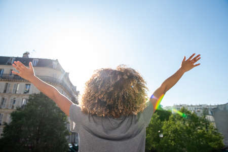 Portrait from behind young african american woman with arms raised outdoorsの写真素材