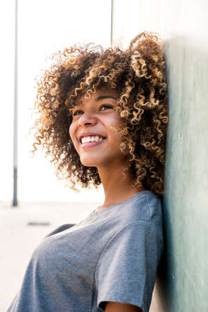 Side portrait happy african american girl leaning against wallの写真素材