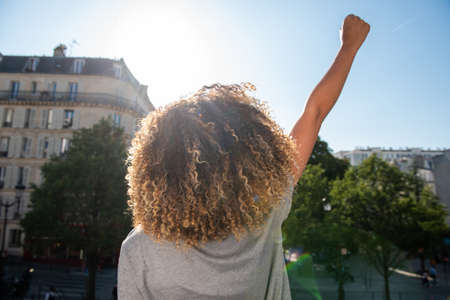Portrait from behind young african american woman with arm raised fistの写真素材
