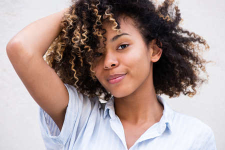 Close up portrait beautiful young black woman with hand in curly hair