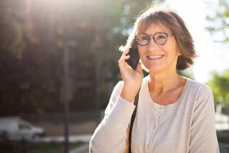Close up portrait happy woman with glasses talking on cellphoneの写真素材