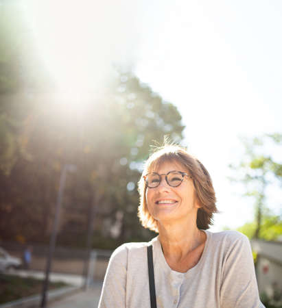 Close up portrait smiling older woman with eyeglasses outside